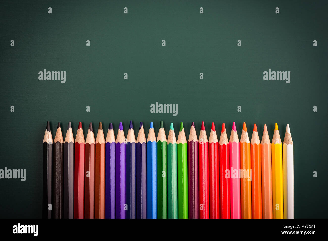 Bottom border of colorful pencil crayons against a green blackboard