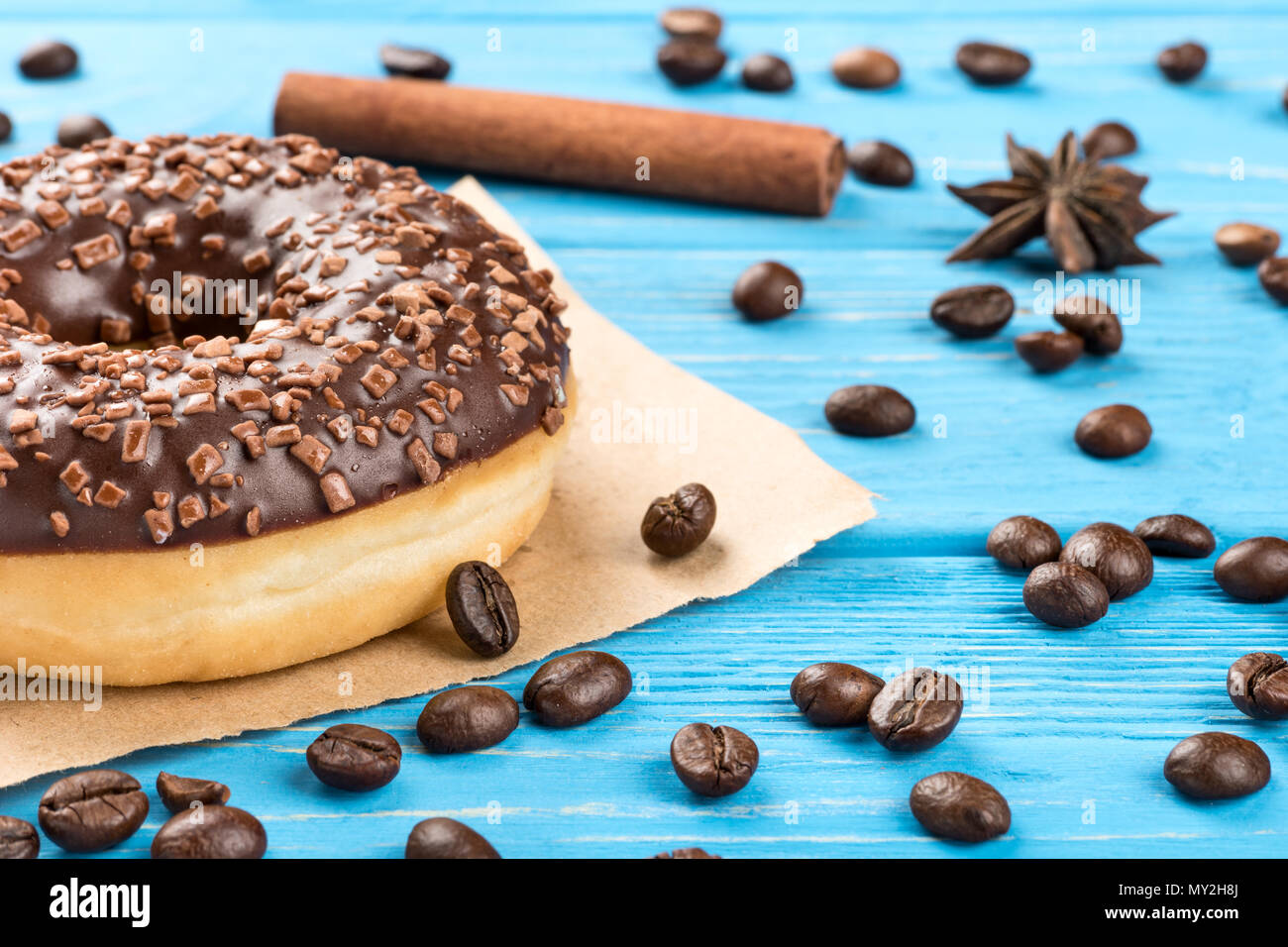 Delicious chocolate donut with scattered beans on the table close-up Stock Photo