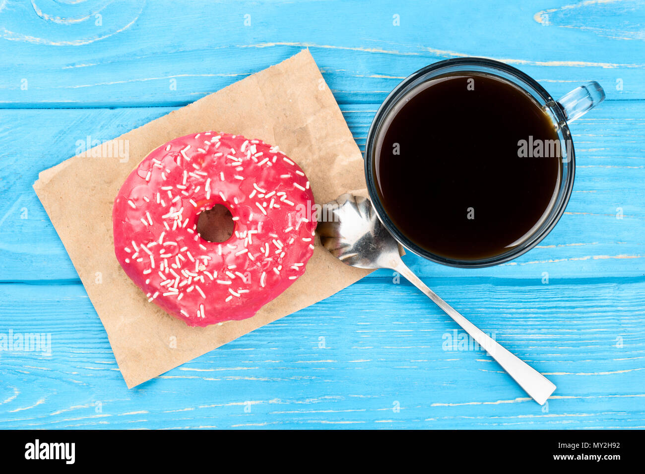 Tasty pink donut with a cup of coffee on a blue table, top view Stock Photo