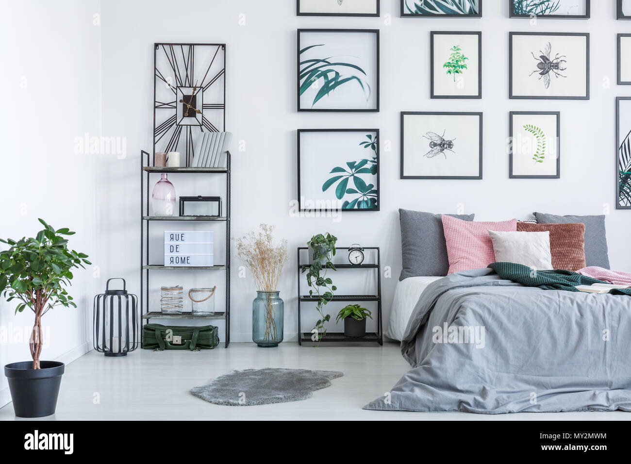 Real photo of a bed standing next to the shelves with ornaments and