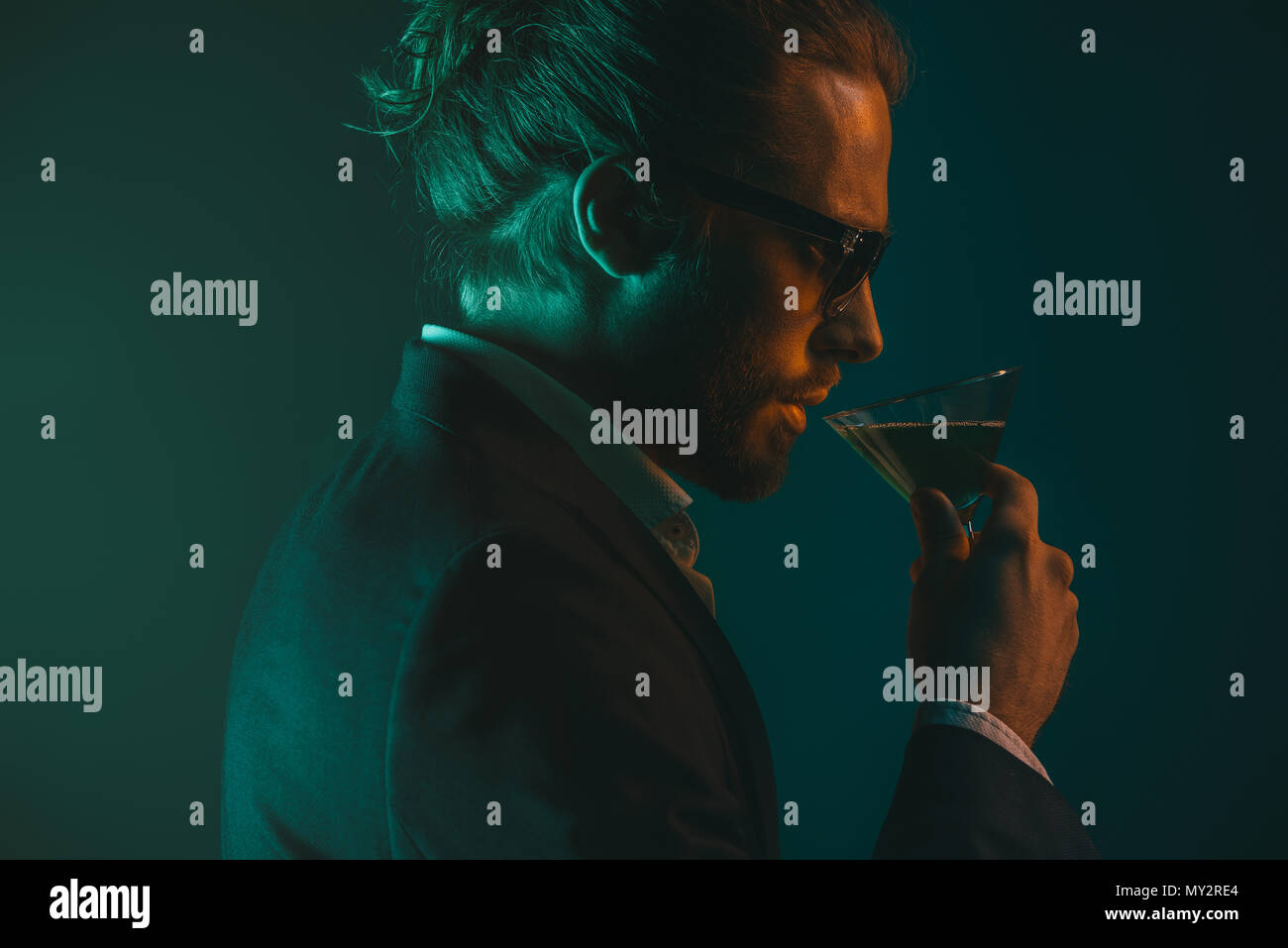 profile of young caucasian man in suit drinking cocktail from glass ...