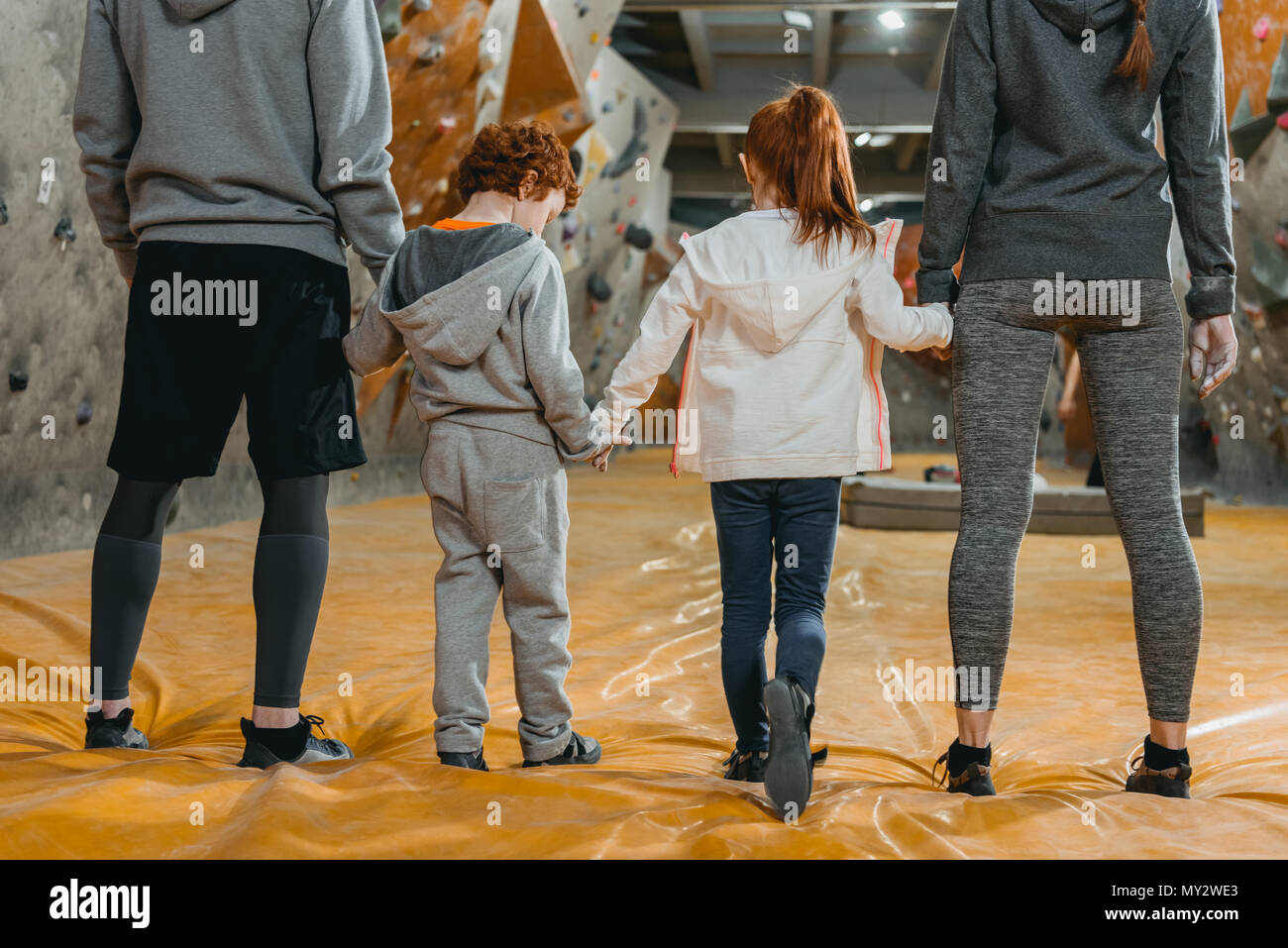 Cropped shot of family with kids holding hands and standing in a row at gym Stock Photo