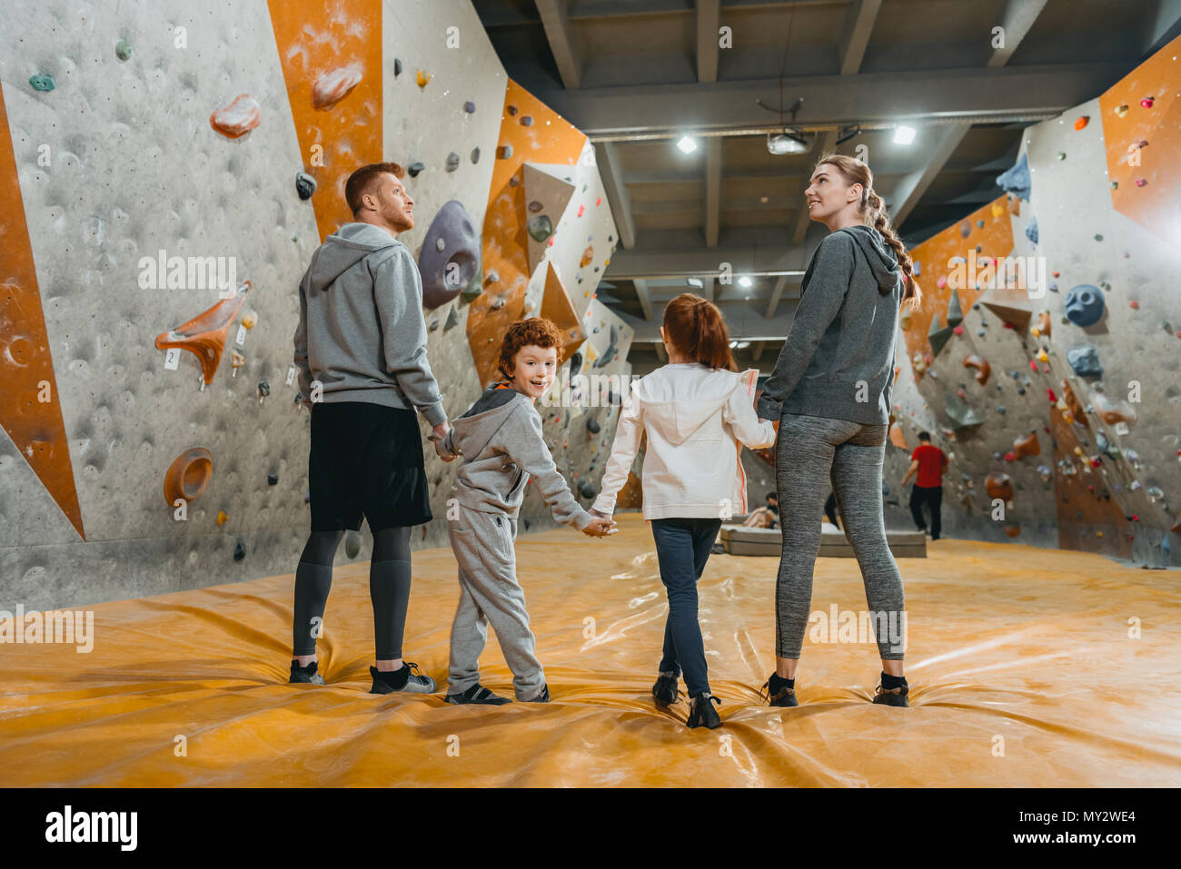 Full-length shot of family with kids holding hands and standing in a row at gym Stock Photo