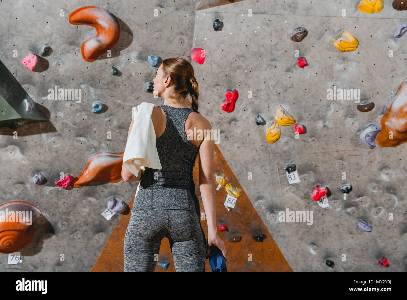 Rear view shot of a young woman in sportive attire posing in front of climbing wall Stock Photo