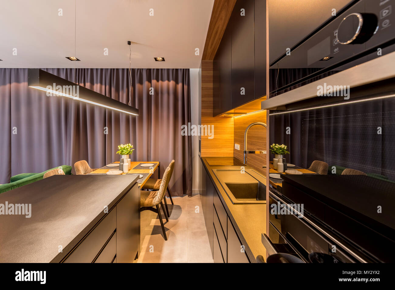 Dark Kitchen In Open Space Interior With Chair At Dining Table