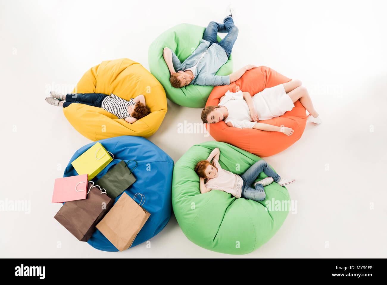 high angle view of family with two children resting on bean bag chairs ...
