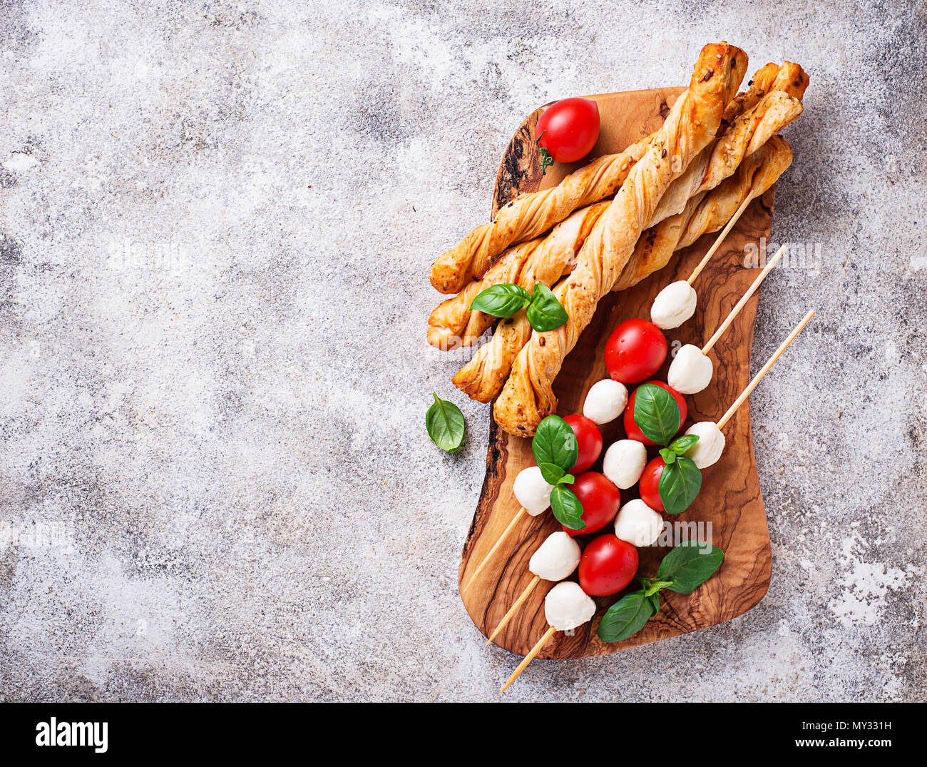 Traditional Italian antipasto caprese skewers and grissini bread Stock