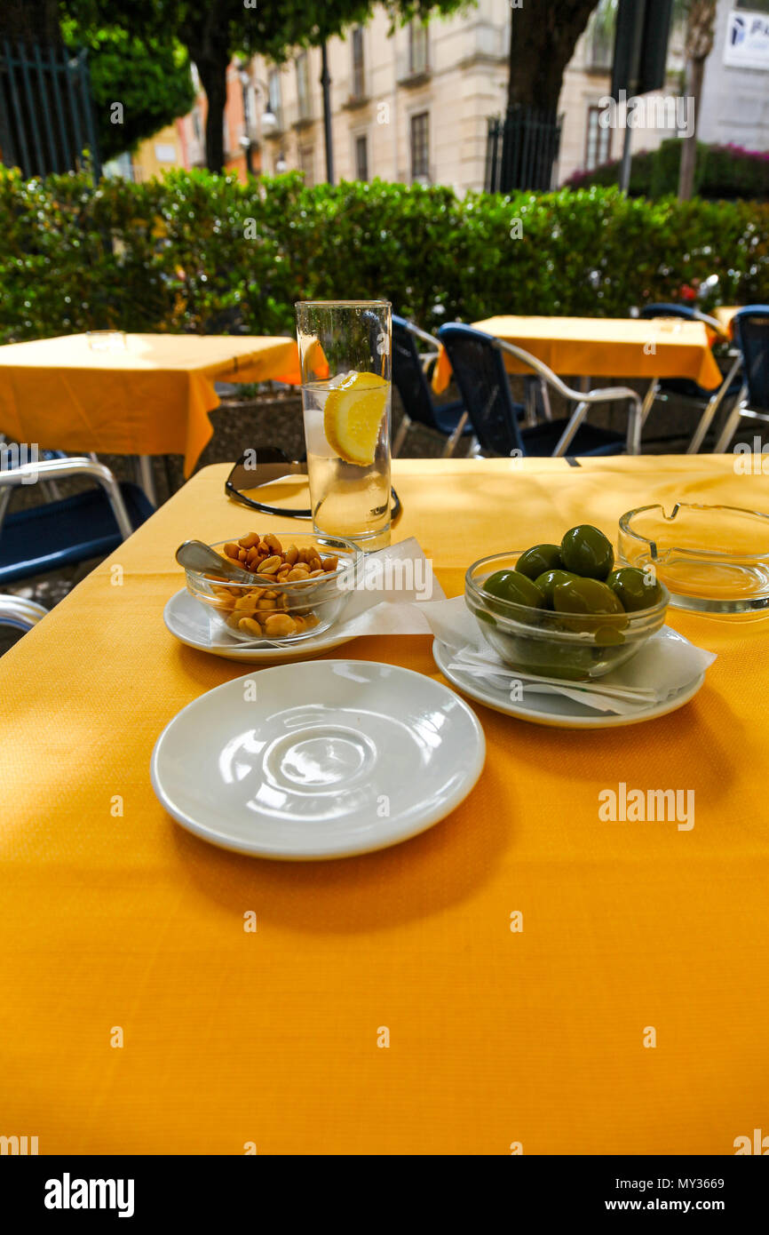 Olives and peanuts on a café table as a side order to a gin and tonic drink Stock Photo