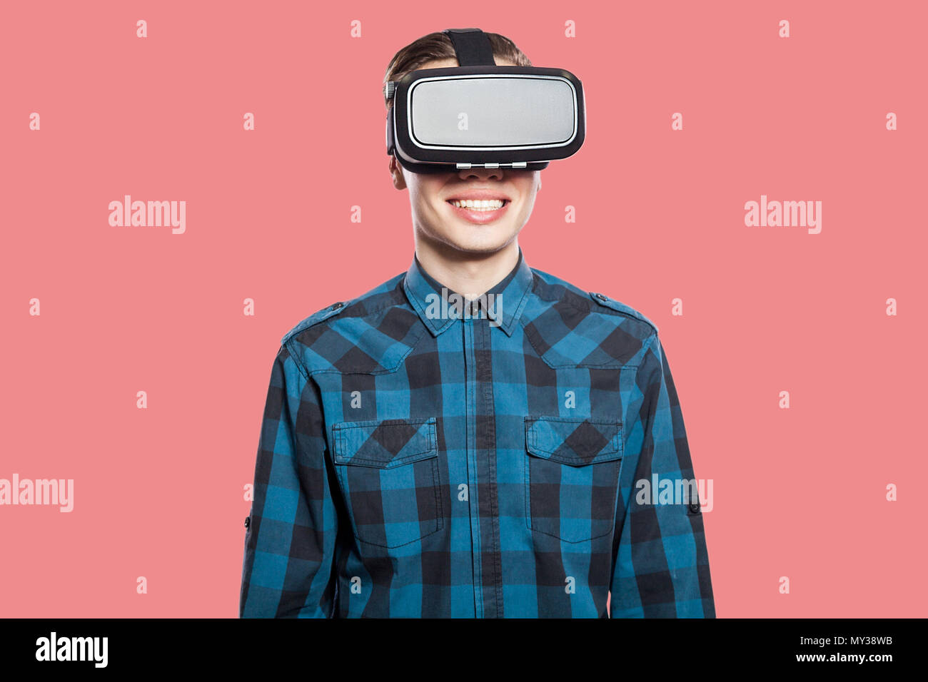 Happy smiling young man with vr headset. studio shot, isolated on pink background. Stock Photo