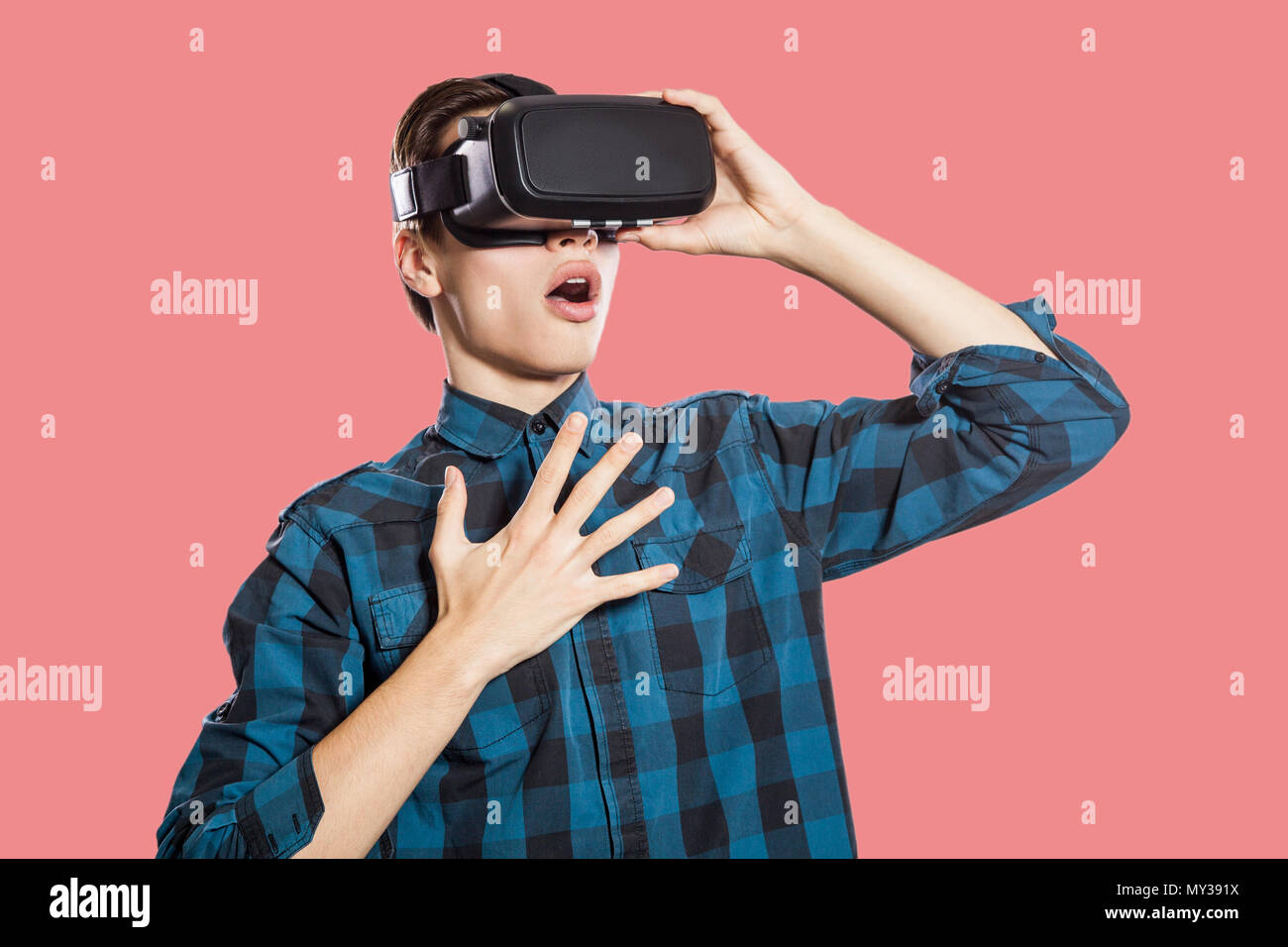 surprised young man with vr headset. studio shot, isolated on pink background. Stock Photo