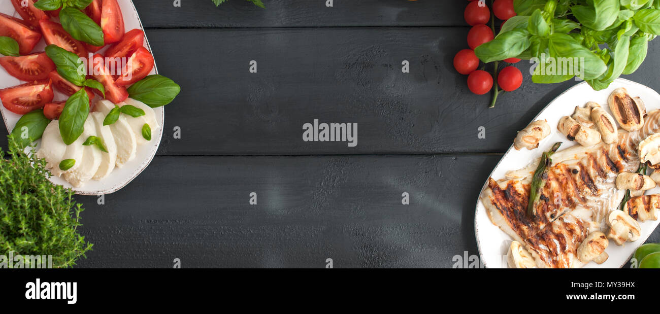 Different food on the table, Italian caprese salad, grilled fish and basil.  A healthy and healthy lunch for the family. Banner. Copy space, above, flat  lay Stock Photo - Alamy