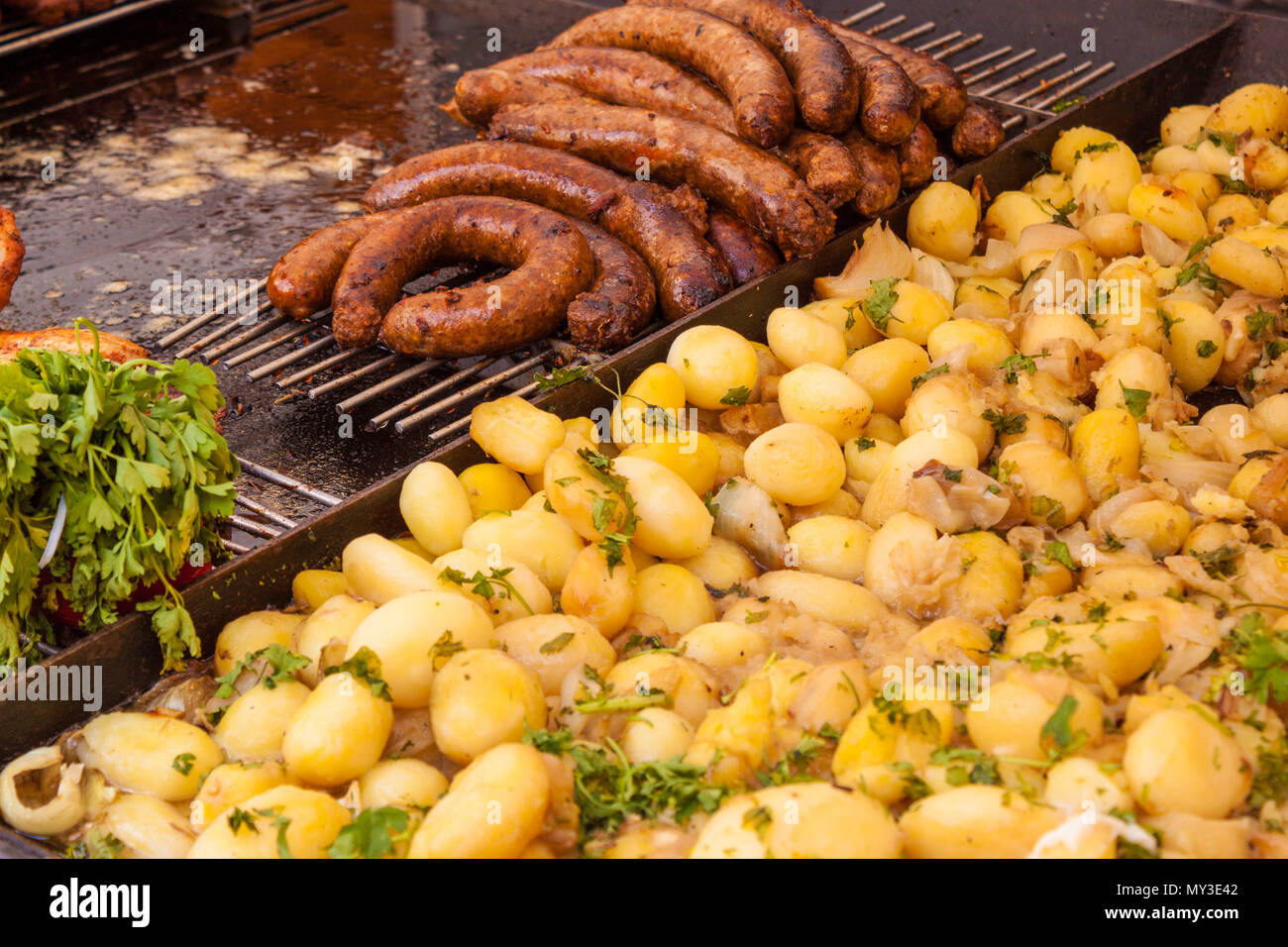 Fried sausages and boiled potatoes with parsley on an outdoor market stall in Budapest, Hungary. Typical european street food. Stock Photo