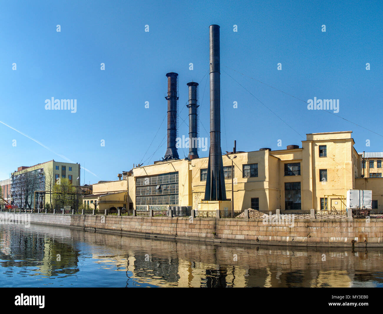 Industrial building of yellow color with black pipes  near the river Moika in the city of Saint-Petersburg Stock Photo