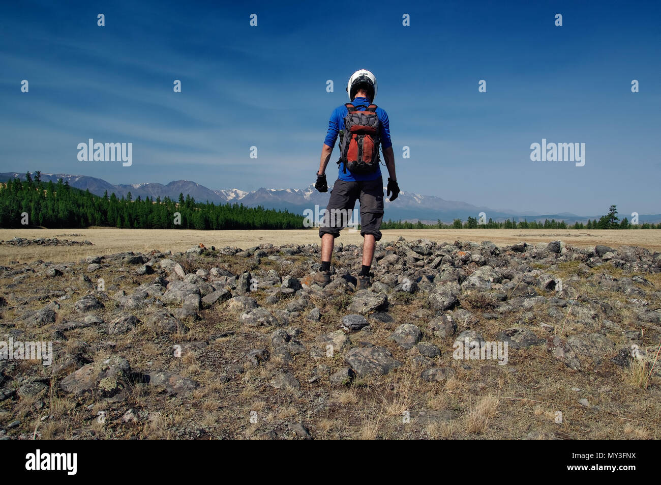 Motorcyclist man in helmet standing on archaeological excavations on the site of ancient Scythian burials of Pazyryk culture  Altai mountains, Siberia Stock Photo
