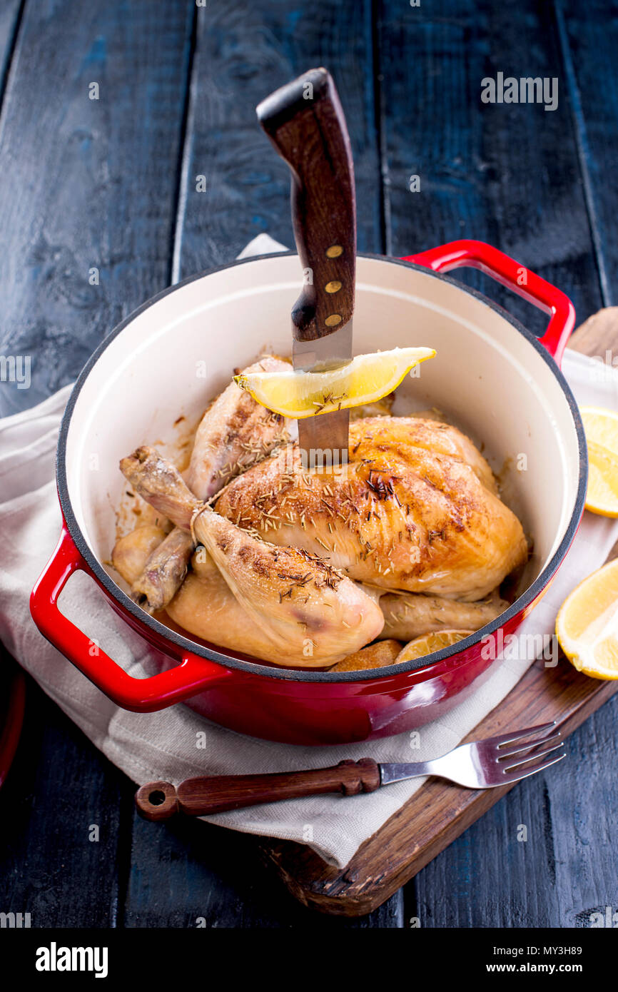 a castiron pot and a golden chicken with lemon and rosemary from the