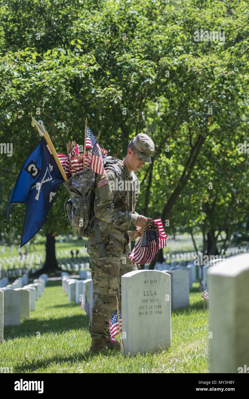 A Soldier from the 3d U.S. Infantry Regiment (The Old Guard) places U.S. flags at headstones in Section 43 during Flags In at Arlington National Cemetery, Arlington, Virginia, May 24, 2018, May 24, 2018. For more than 60 years, Soldiers from the Old Guard have honored our nation's fallen heroes by placing U.S. flags at gravesites for service members buried at both Arlington National Cemetery and the U.S. Soldiers' and Airmen's Home National Cemetery just prior to the Memorial Day weekend. Within four hours, more than 1, 000 Soldiers placed 234, 537 flags in front of every headstone and Columba Stock Photo