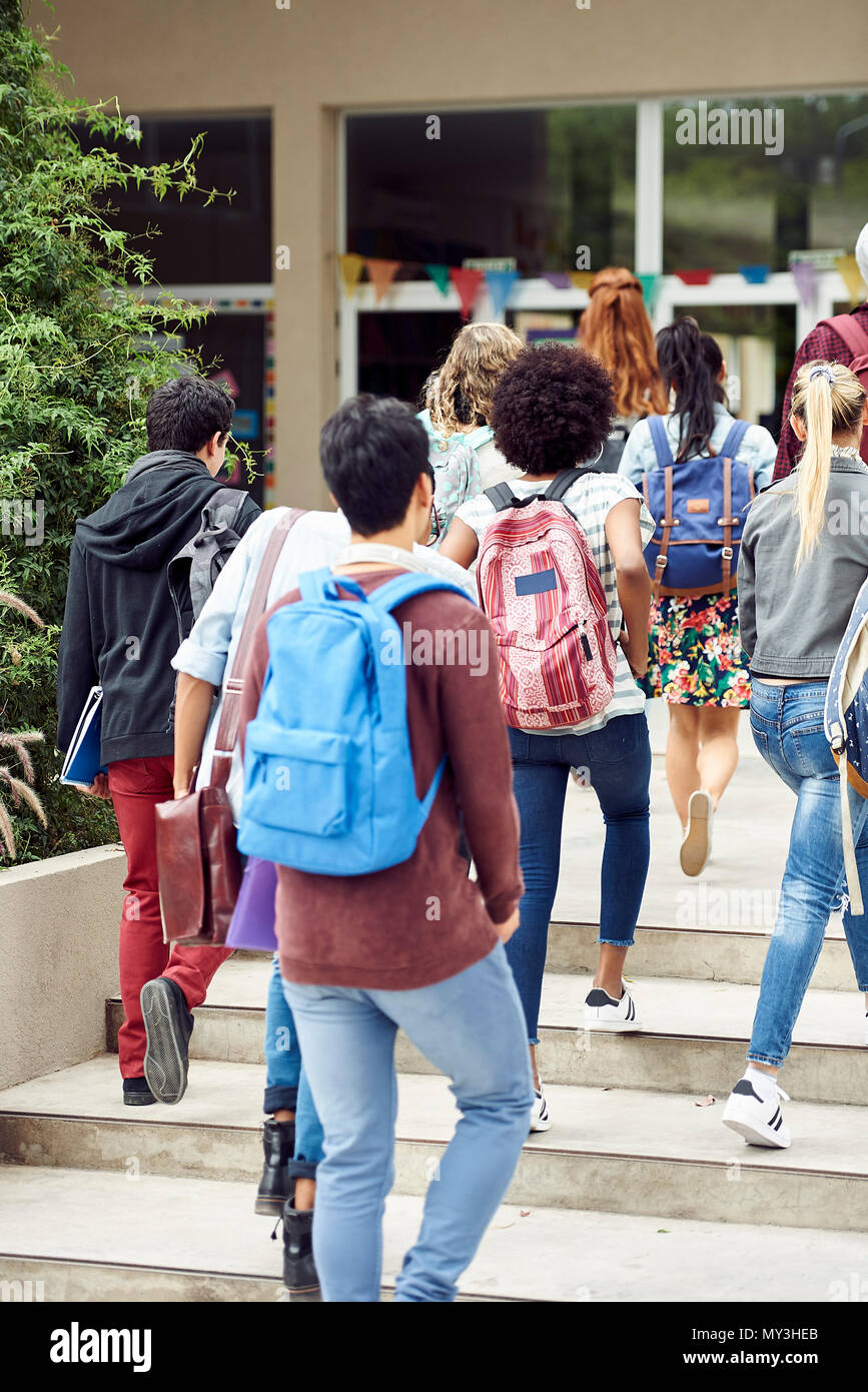 College students walking toward campus building, rear view Stock Photo