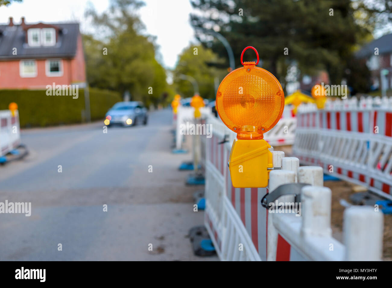 red and white barricades with warning lights at a street in the residential zone, depth of field Stock Photo