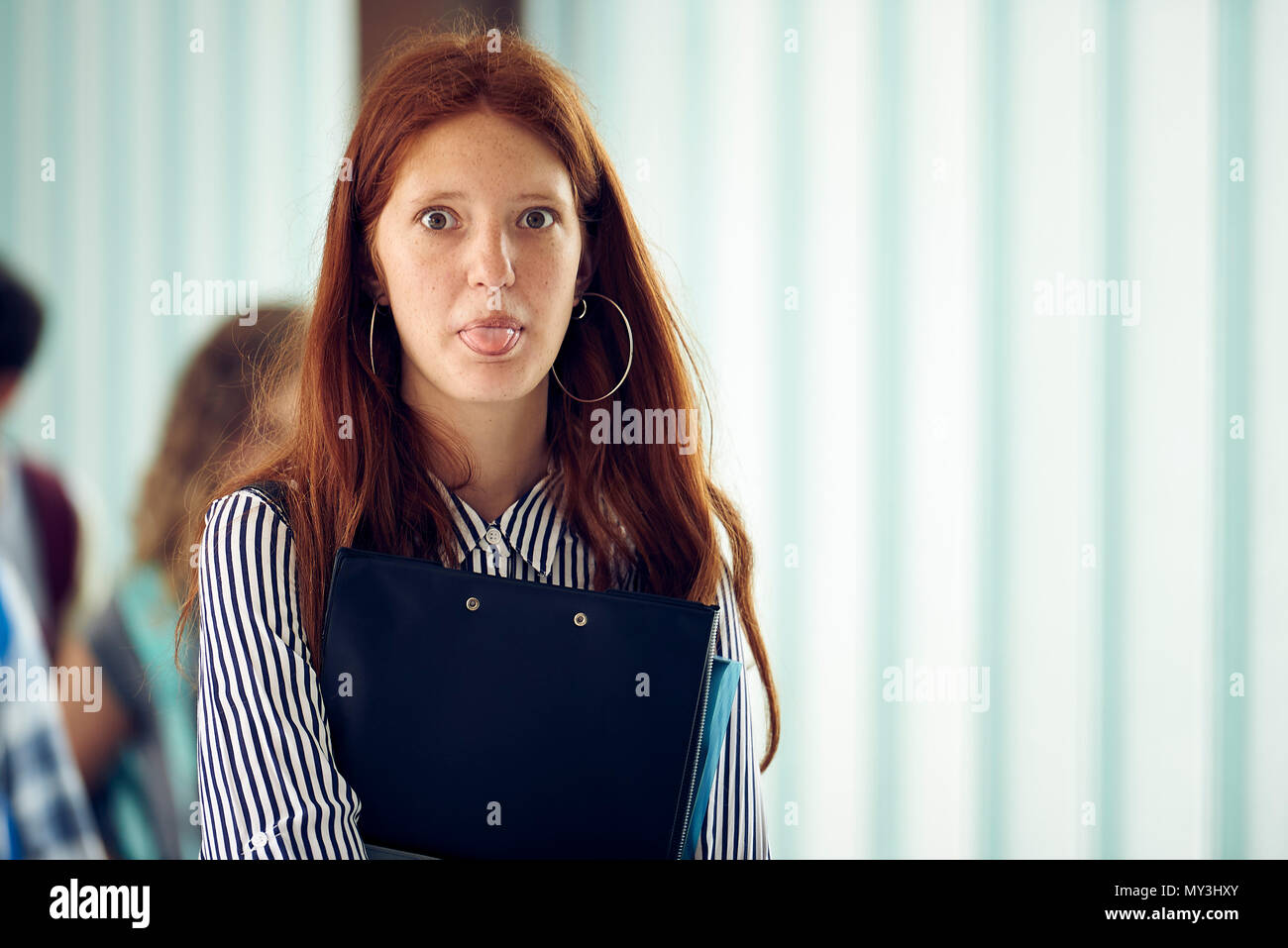 Young woman sticking out tongue in corridor Stock Photo