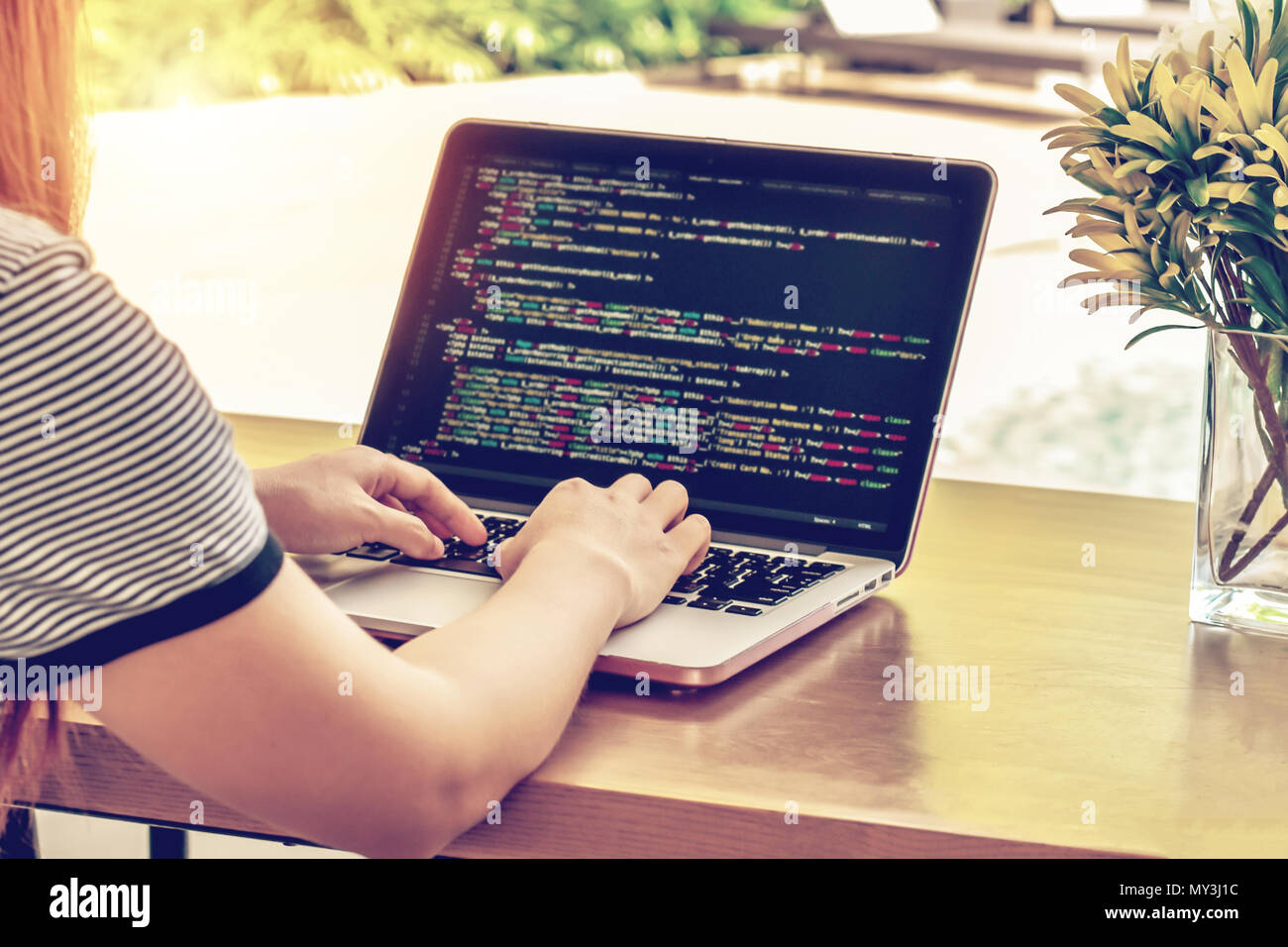 Close-up of programmer's hands working on source codes over a laptop on a summer day. Stock Photo
