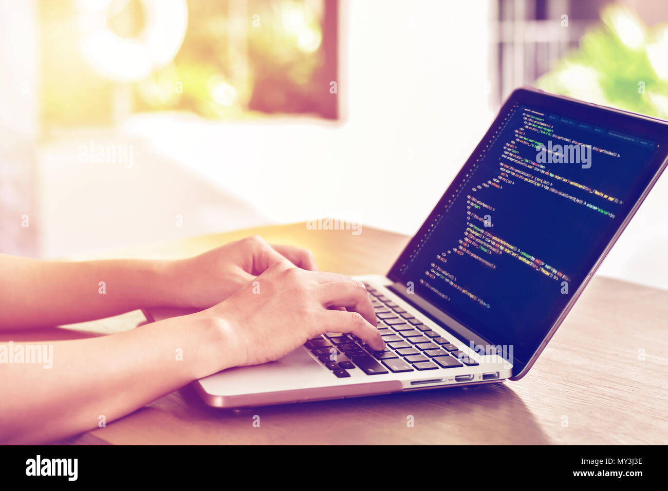 Close-up of programmer's hands working on source codes over a laptop on a summer day. Stock Photo