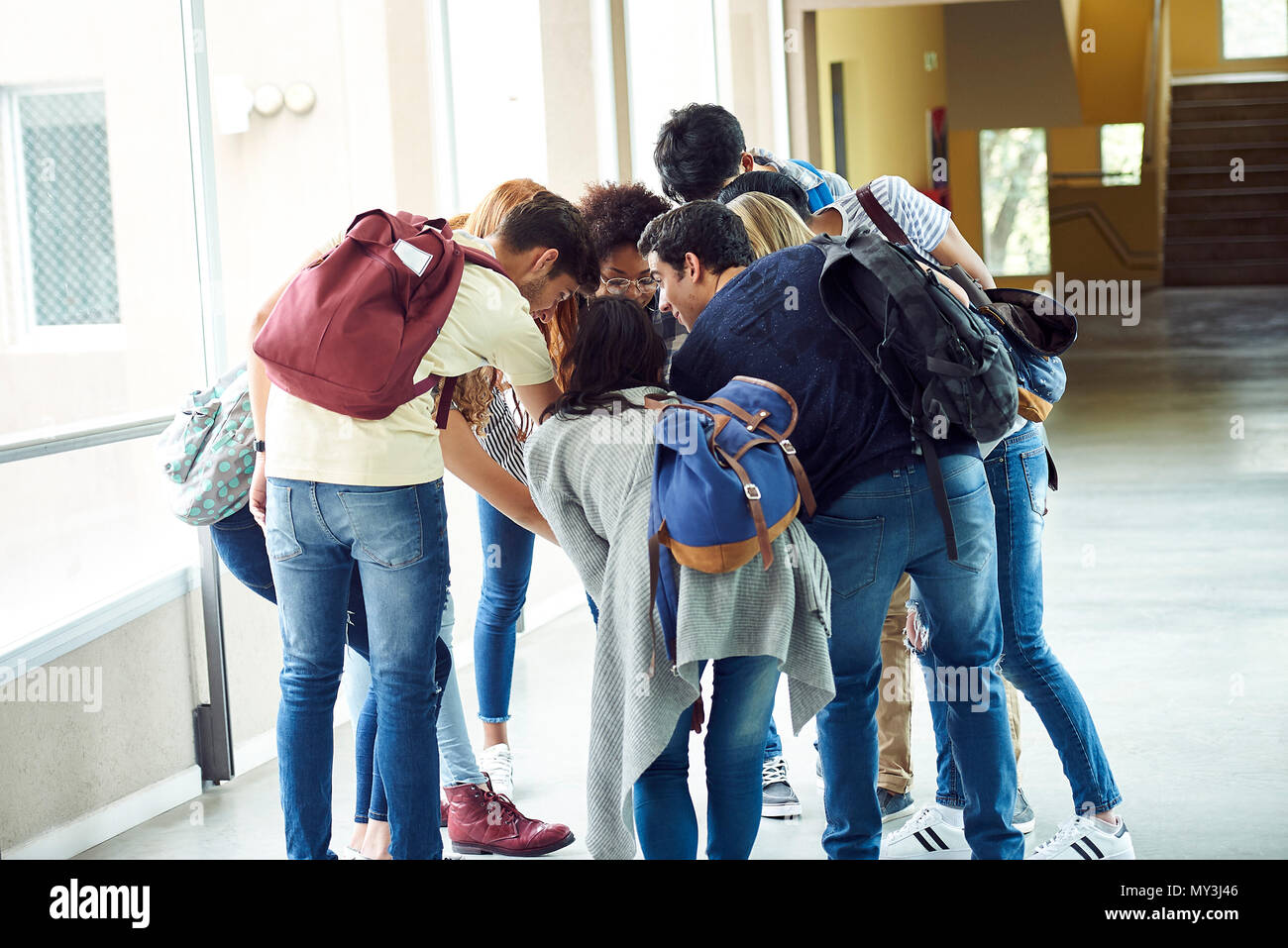 Group of students bending forward in a circle together in school corridor Stock Photo