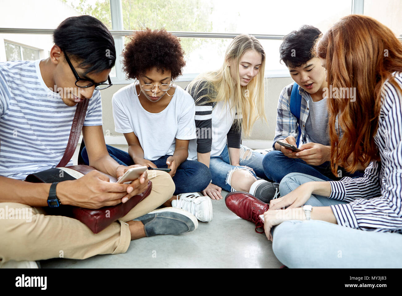 Students sitting together using smart phones Stock Photo
