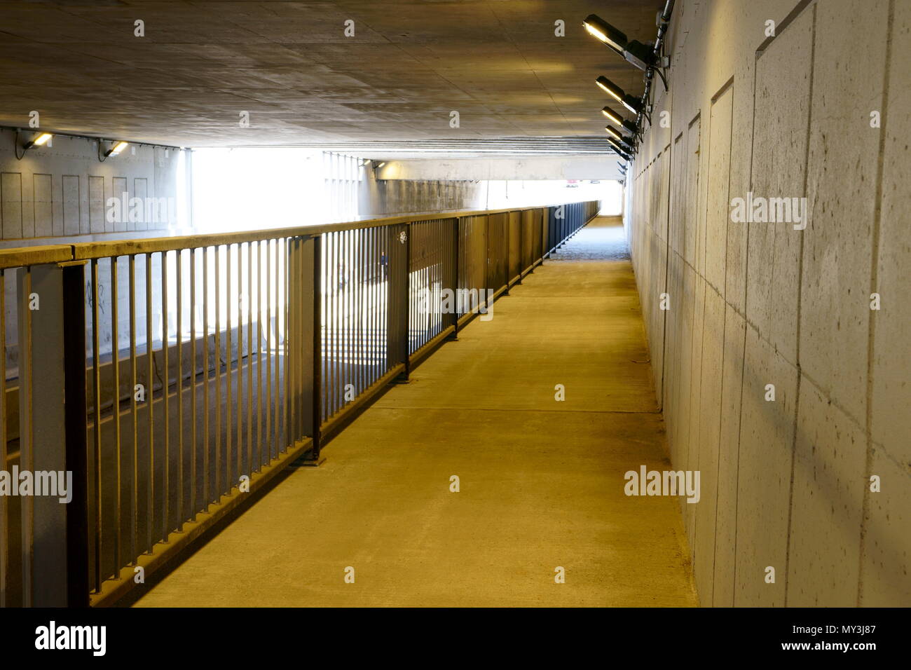 An empty underpass with nobody, made of concrete during the day, yellow lights opened. Stock Photo