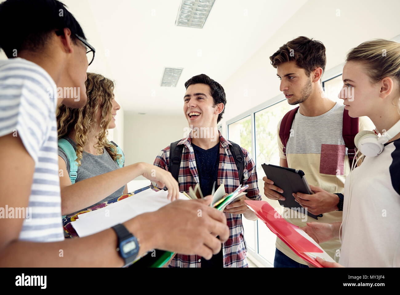 Group of students chatting together in school corridor Stock Photo