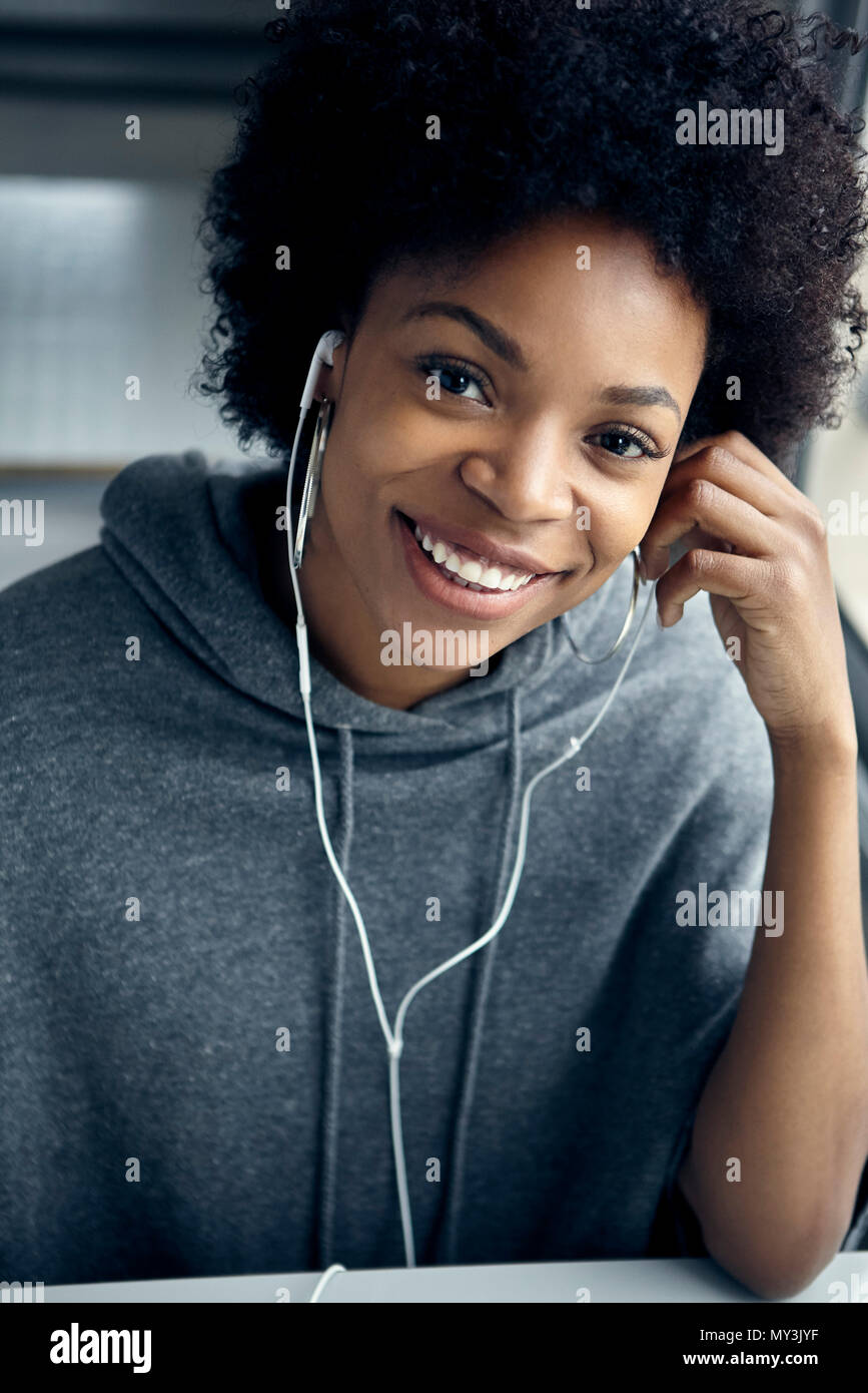 Young woman listening to earphones and smiling cheerfully, portrait Stock Photo