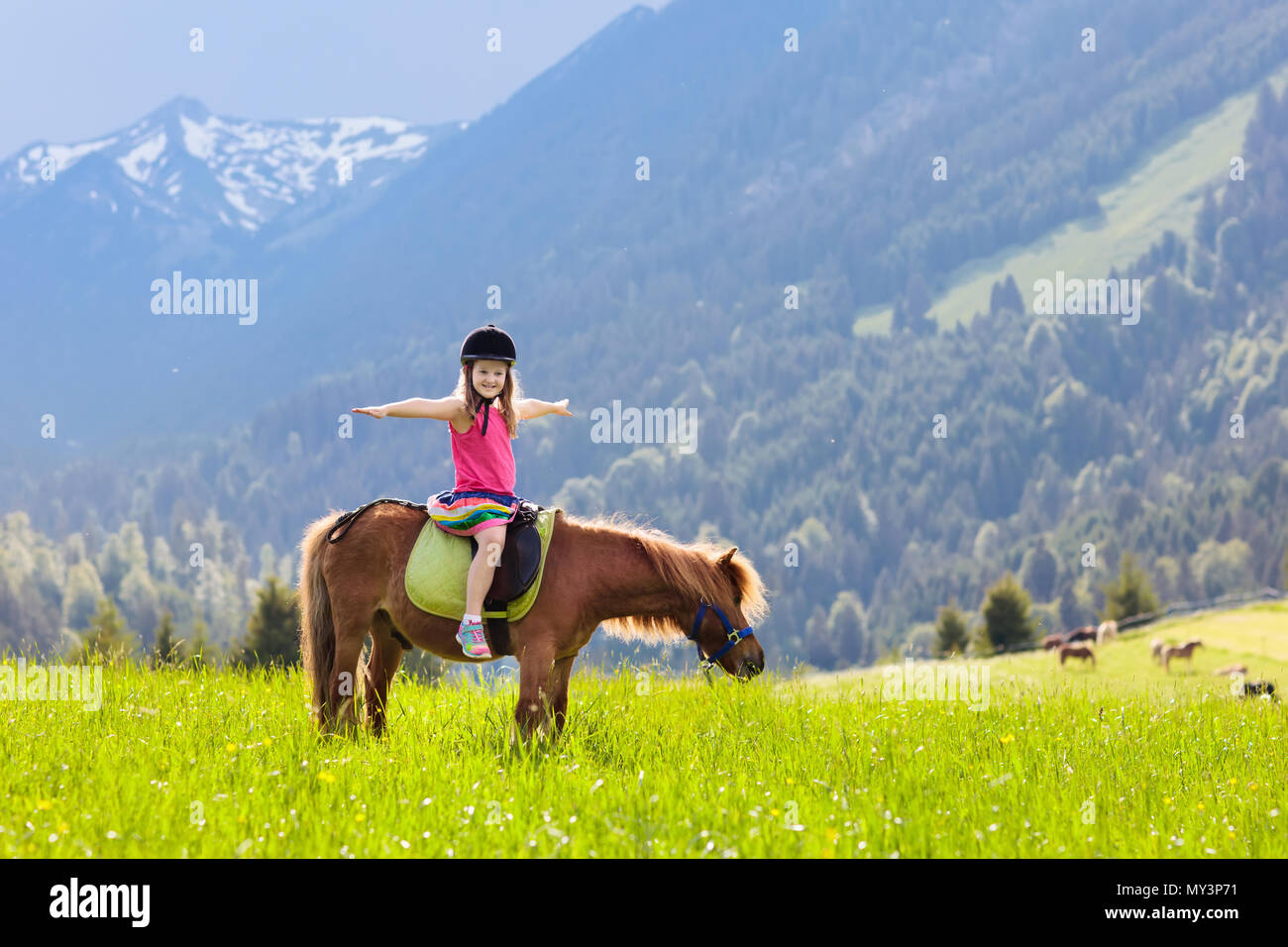 Kids riding pony in the Alps mountains. Family spring vacation on horse