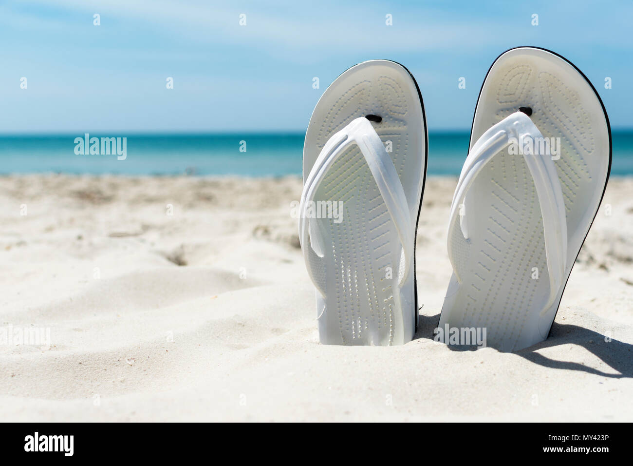 Flip flops in the sand on sea beach background Stock Photo - Alamy