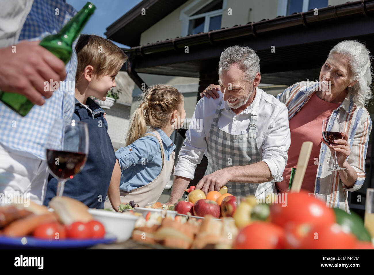 happy grandparents and grandchildren preparing food on picnic outdoors Stock Photo