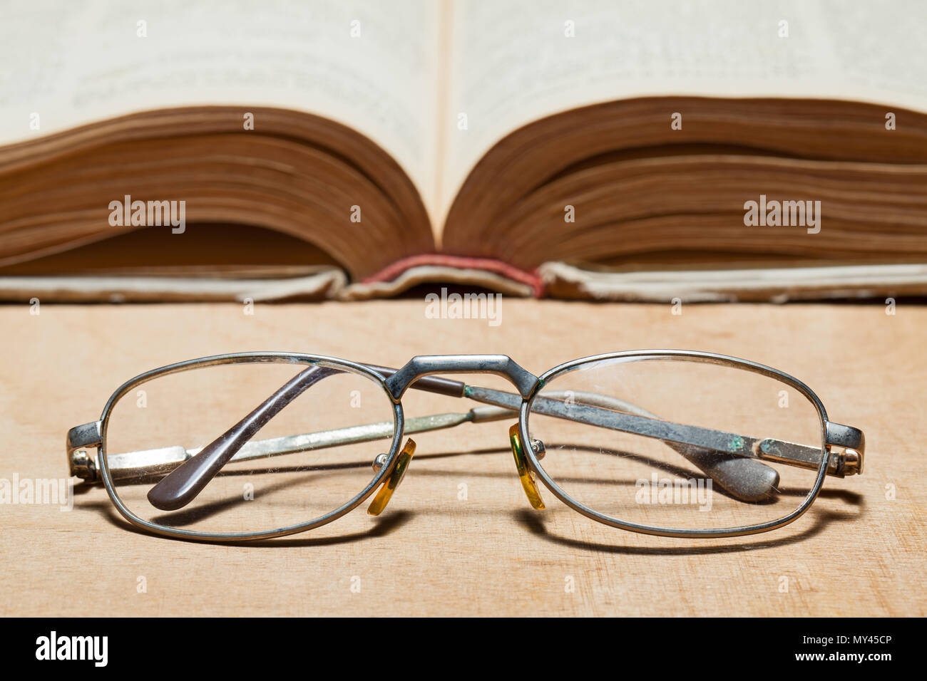 Open old book and glasses. Selective focus. Stock Photo