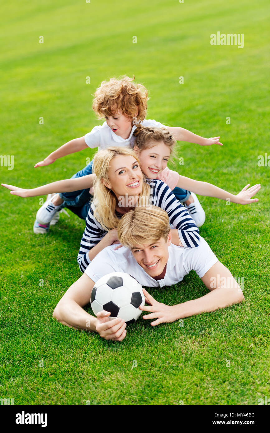 happy young family with soccer ball lying on green lawn at park Stock ...