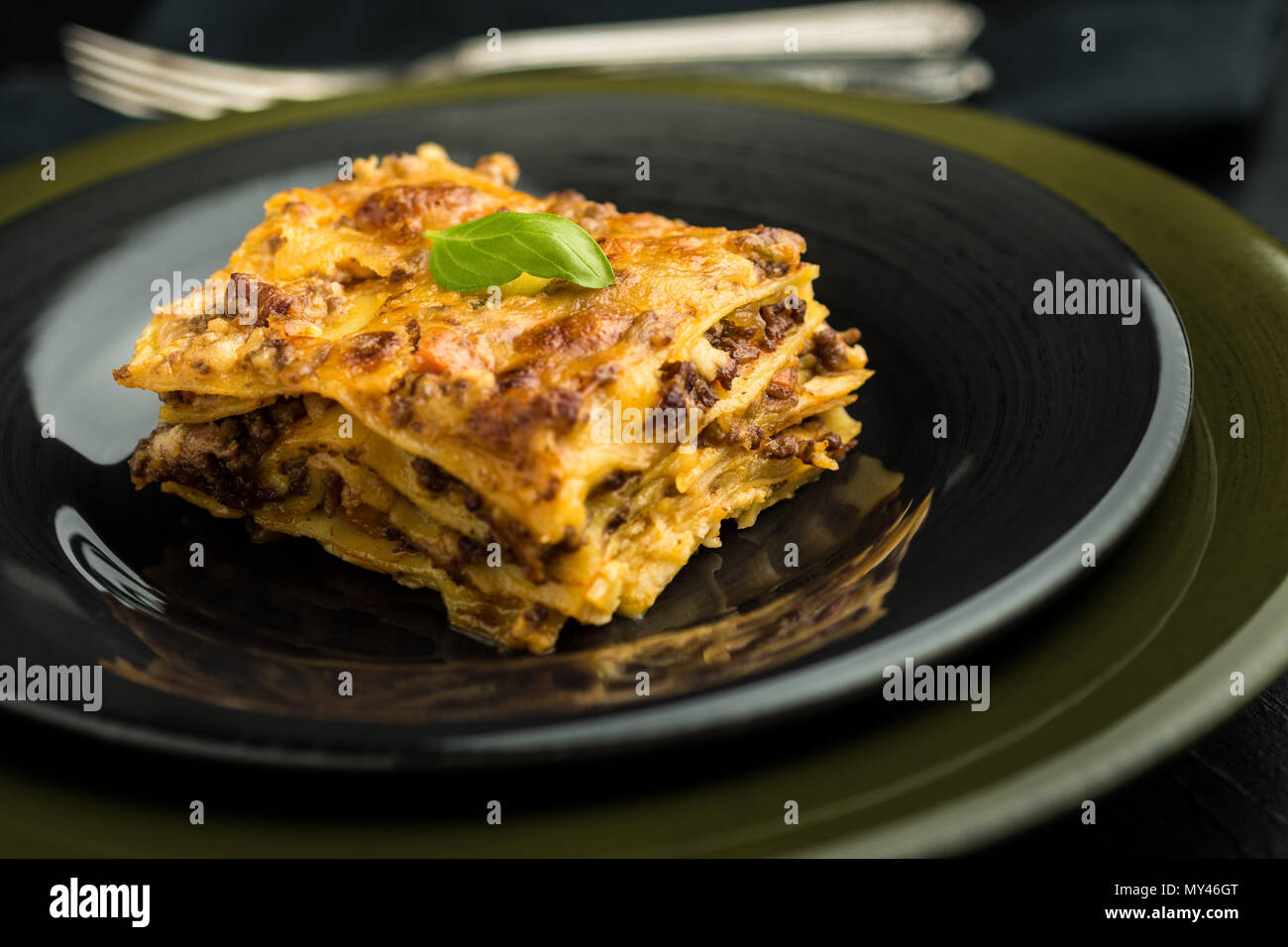 Traditional Lasagna With Minced Beef, Bolognese Sauce and Basil on Dark Plate. Italian Cuisine. Stock Photo