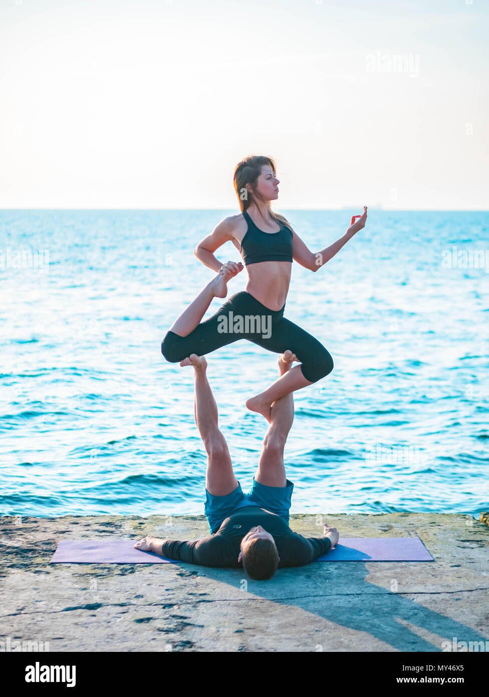 Young beautiful couple practicing acro yoga on the sea beach near water.  Man and woman doing everyday practice outdoor on nature background. Healthy  l Stock Photo - Alamy
