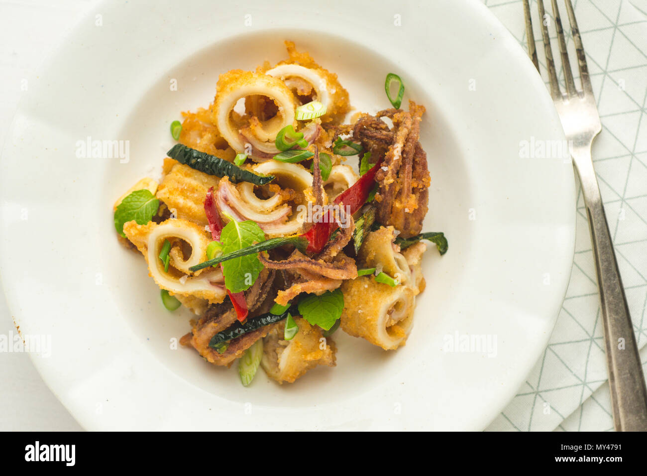 Fried Squids Calamari, Chili Pepper and Mint Leaves on White Plate Stock Photo