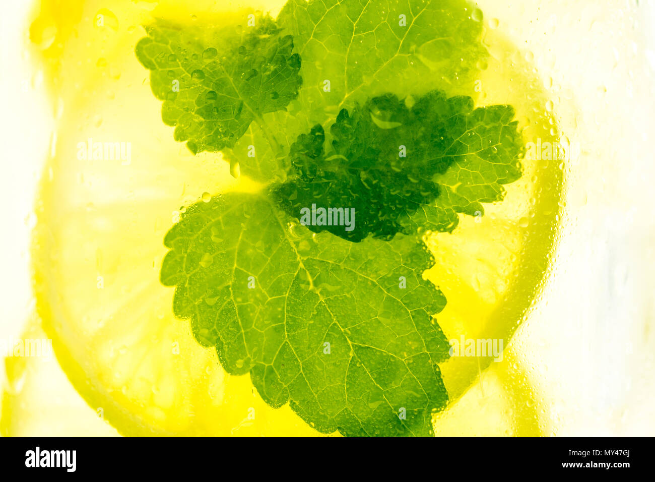 Lemonade Mojito Cocktail with Cold Fresh Ice, Lemon and Mint Leaves in Mason Jar on White Wooden Background. Bright Summer Concept. Stock Photo