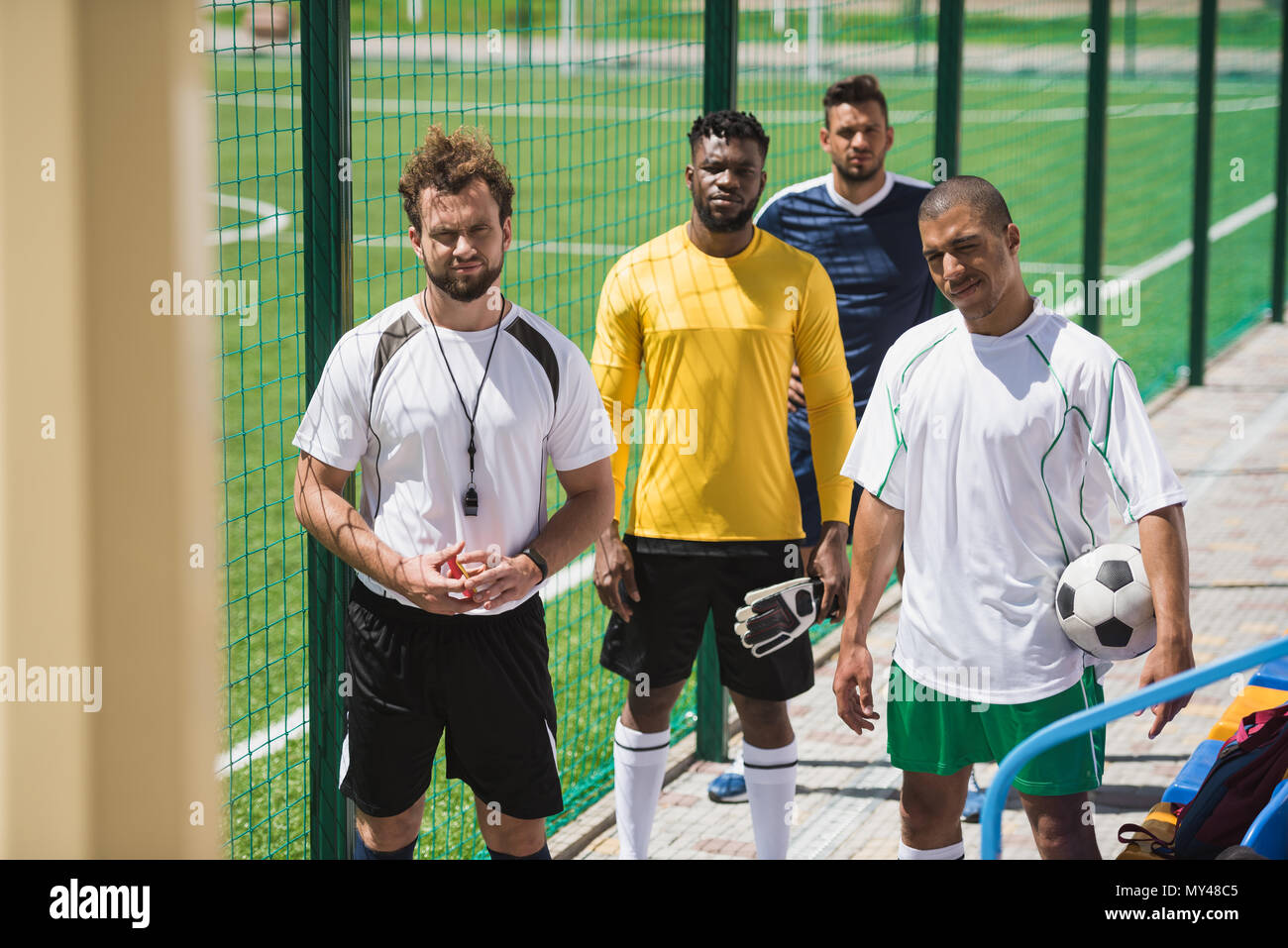 multicultural soccer team and referee standing on stadium before start ...