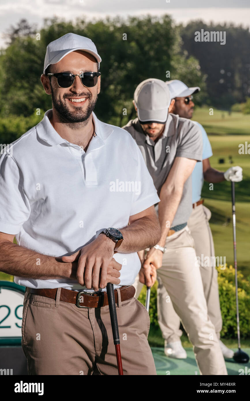 portrait of smiling golfer looking at camera while men playing golf Stock Photo