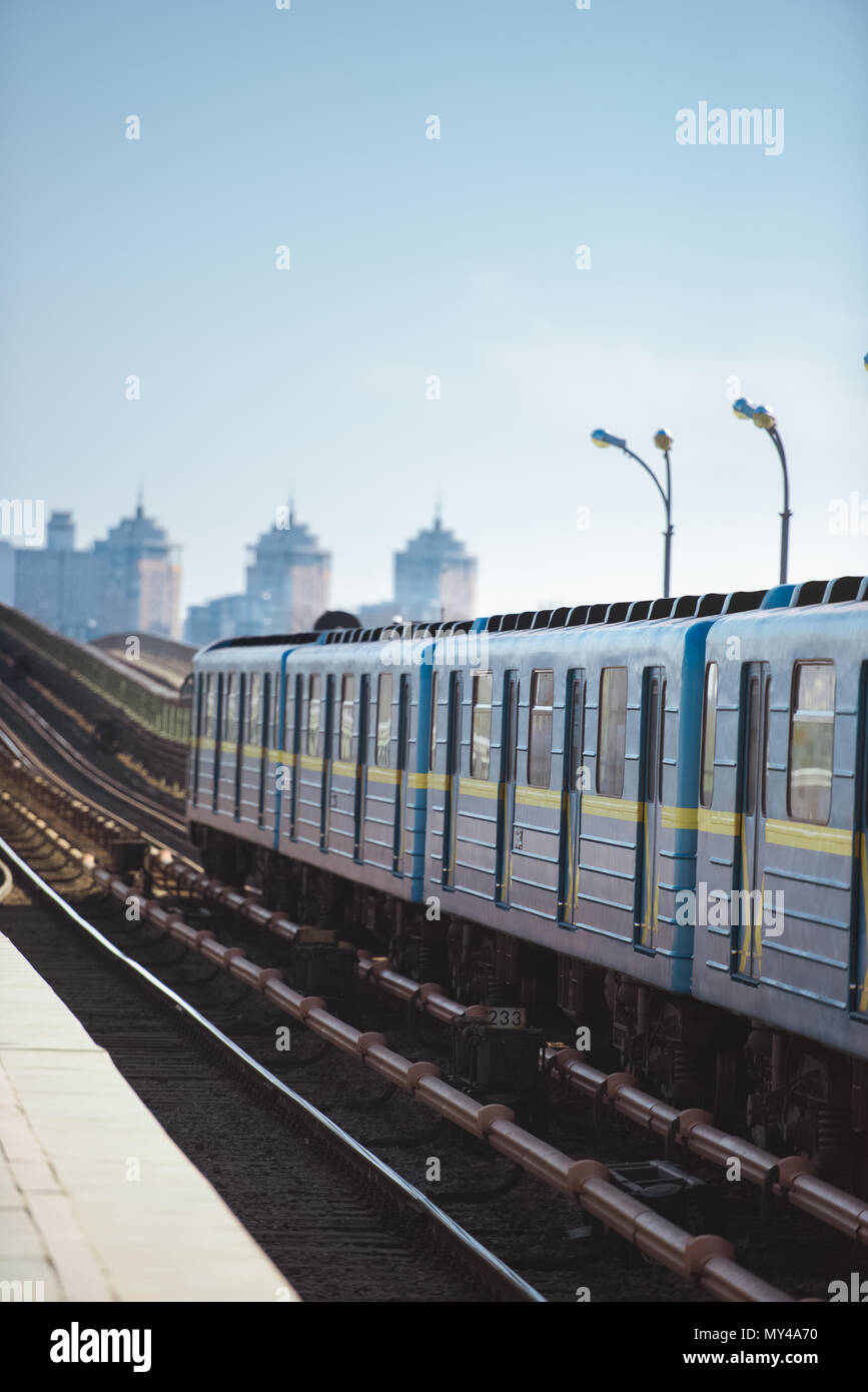 front view of train at outdoor subway station with buildings on ...