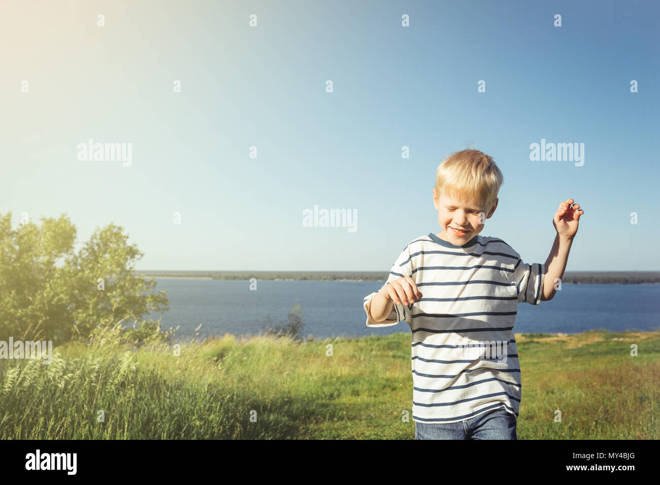 Blond boy joyful and smiling on nature. Summer activity. Stock Photo