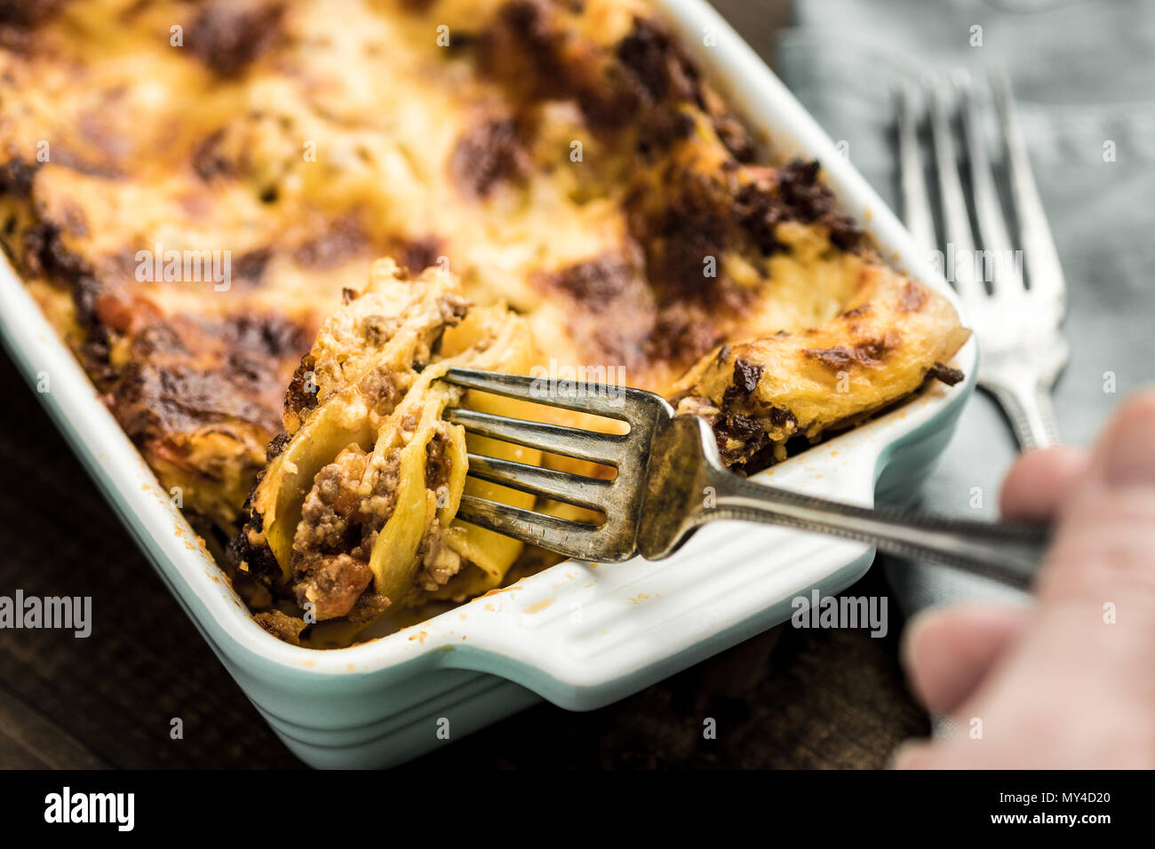 Eating Italian Lasagna with Fork on Dark Wooden Background Stock Photo
