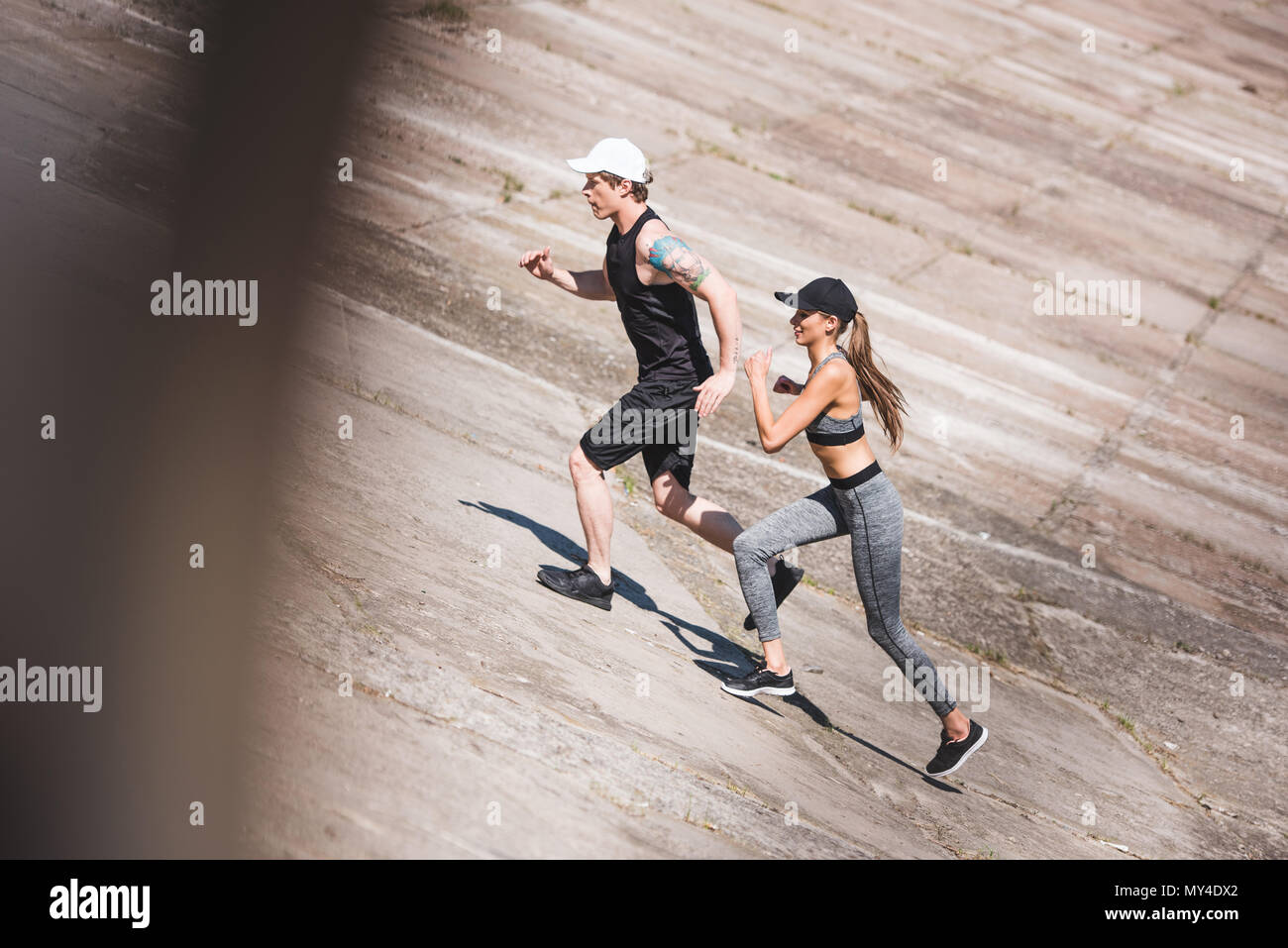 side view of athletic couple jogging together on slabs Stock Photo - Alamy