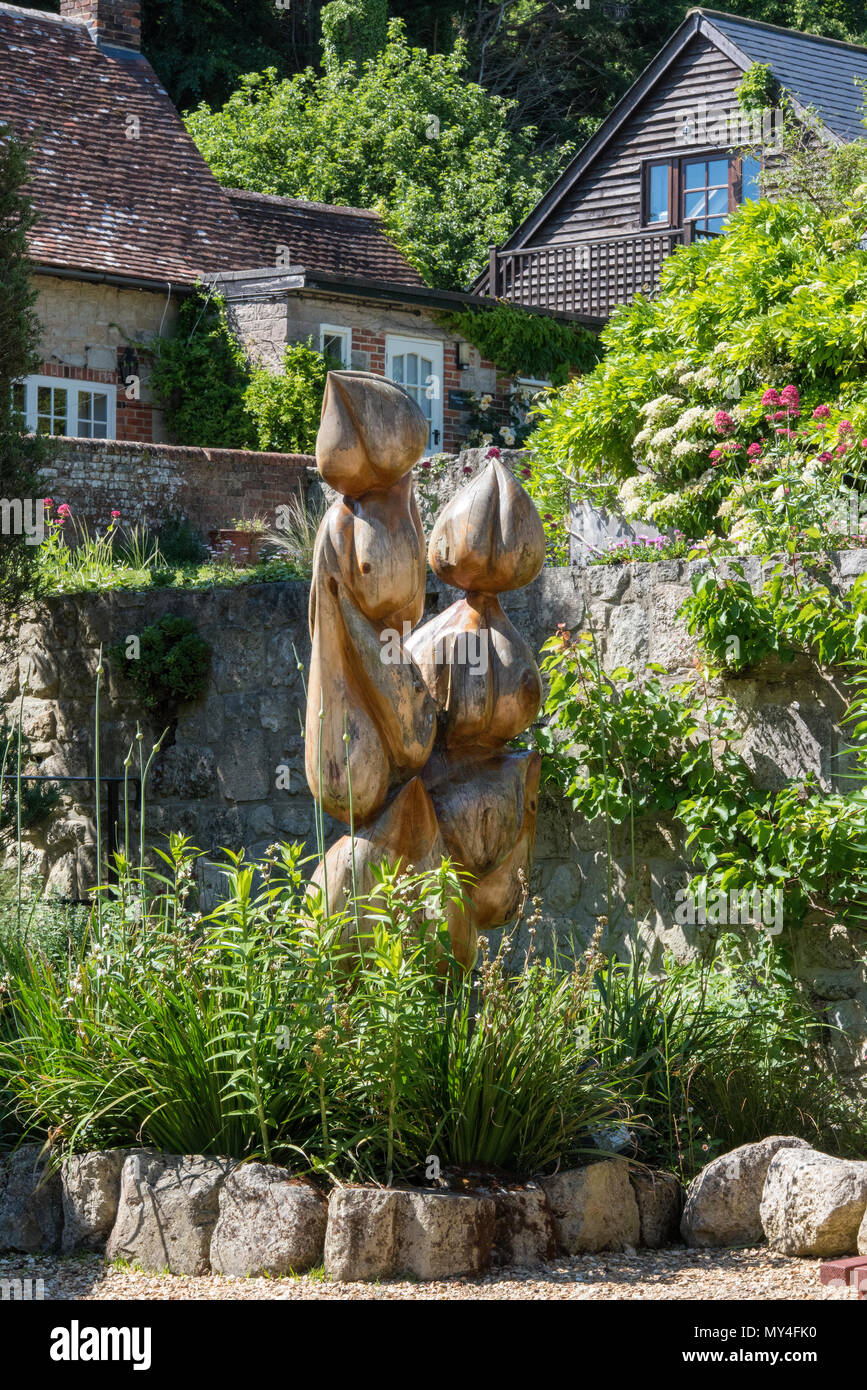 An ornate and feature sized garden sculpture or wood carving outside of picturesque English country cottage in summer.garden decorations and statuary. Stock Photo