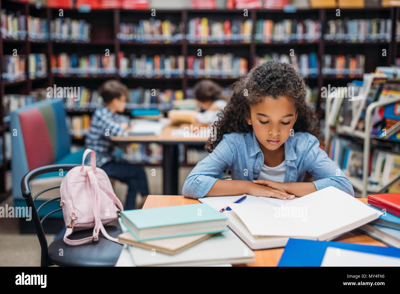 african american schoolgirl reading book in library Stock Photo - Alamy