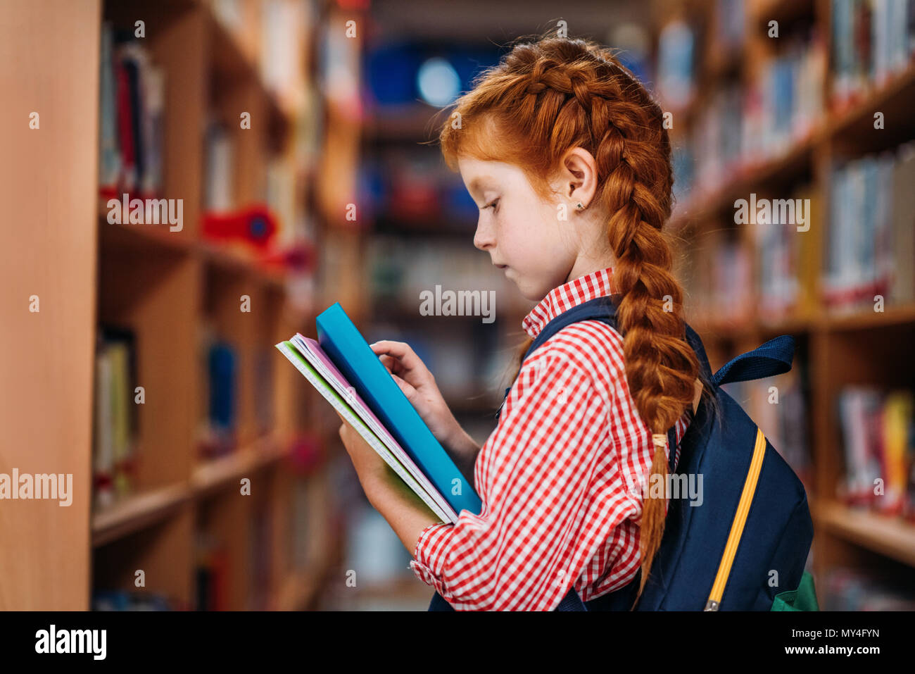 cute redhead schoolgirl with books in library Stock Photo - Alamy