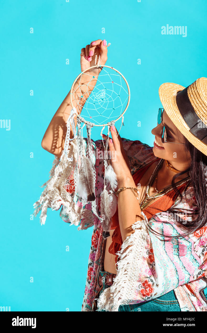hippie girl looking at dreamcatcher isolated on turquoise Stock Photo