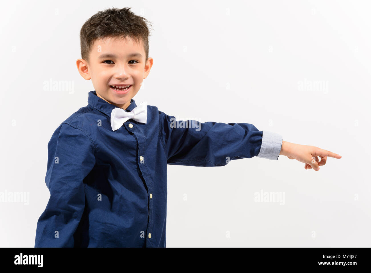 Studio shot of cute happy boy smiling and pointing finger at sid Stock Photo